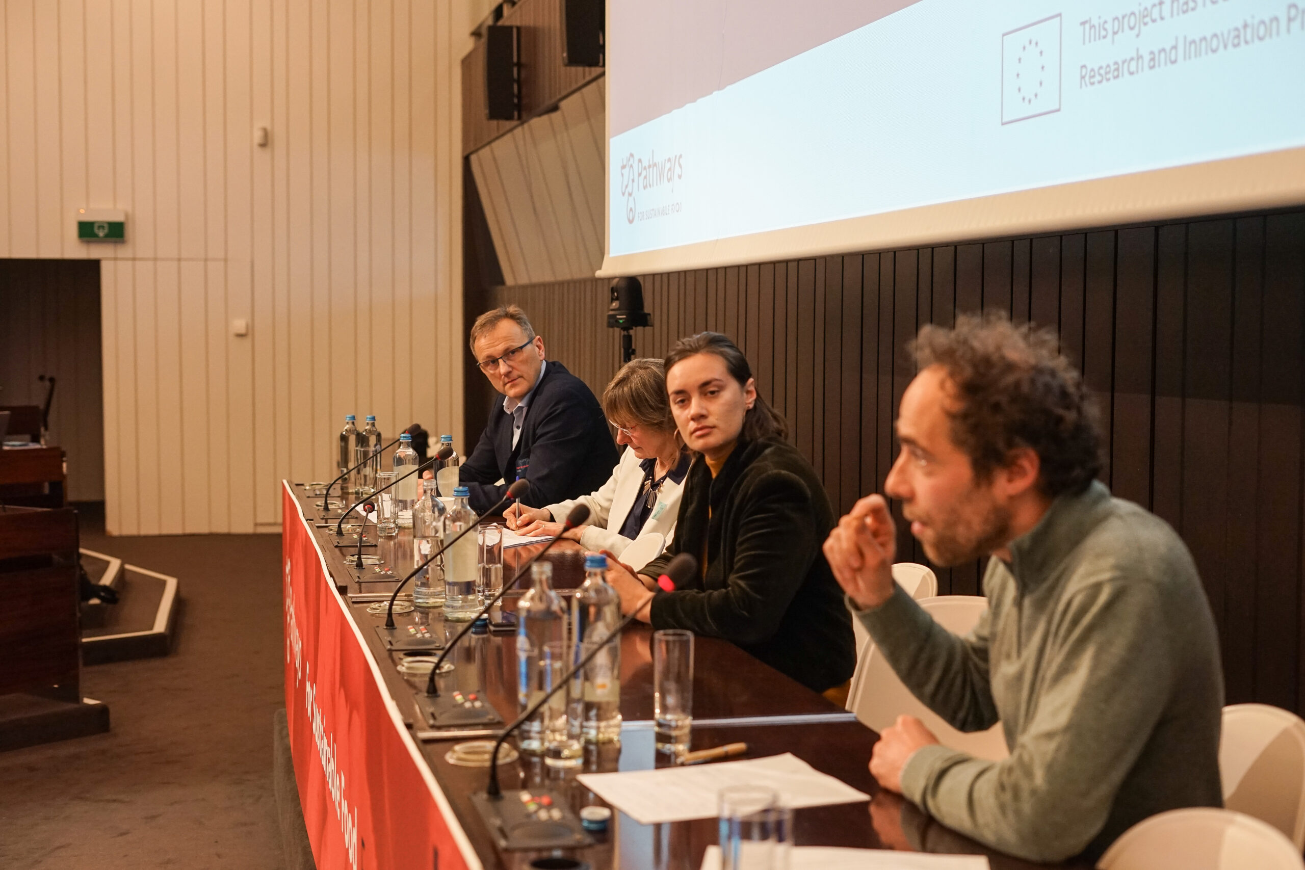 A panel of (L-R) Grzegorz Brodziak, Brigitte Misonne, Natasha Foote and Pierre-Marie Aubert, speak at the For Sustainable Food Forum in Brussels on 7 March 2024. Photo: REVOLVE